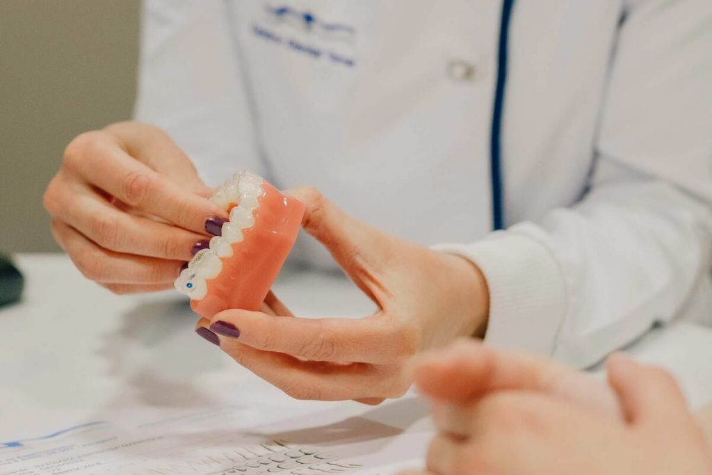 Odontóloga colocando una ortodoncia invisible en una dentadura artificial