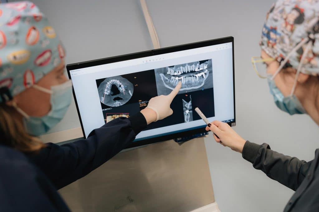 Dos odontólogas de la Clínica Dental Torres viendo en una pantalla una radiografía de las muelas del juicio de un paciente